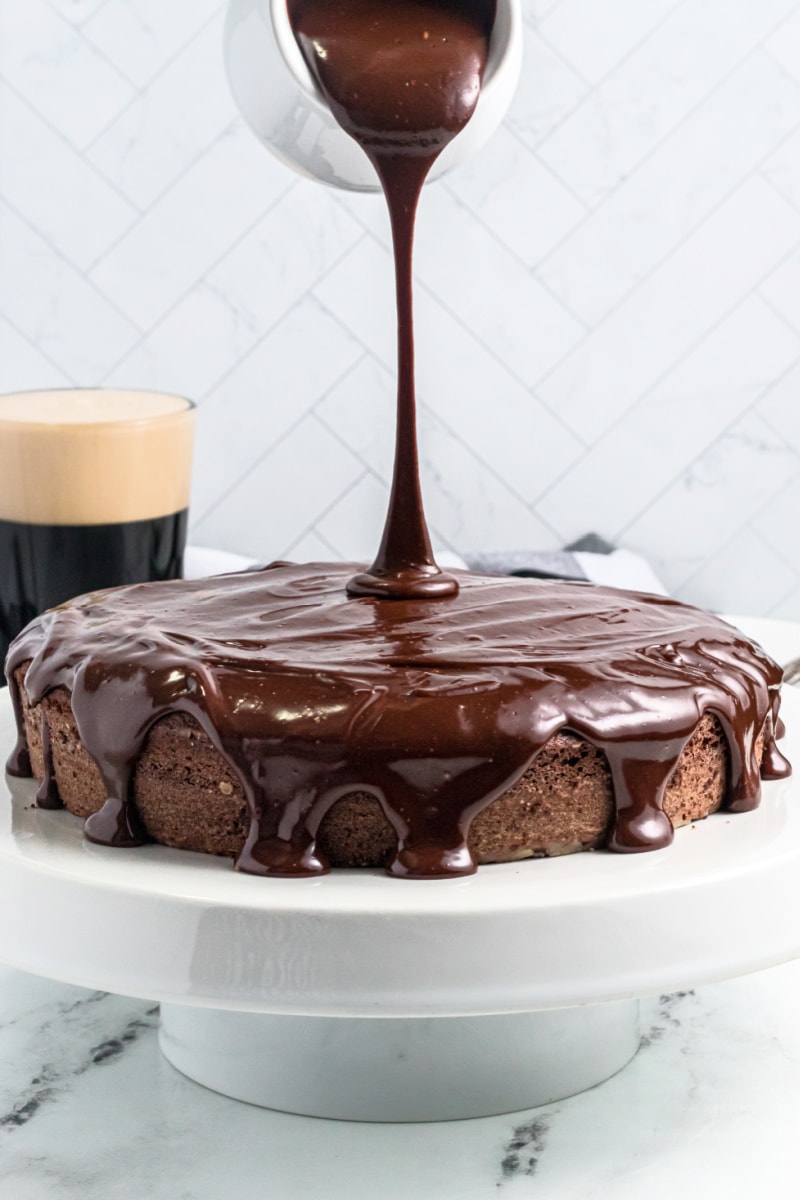 pouring chocolate glaze on top of chocolate cake