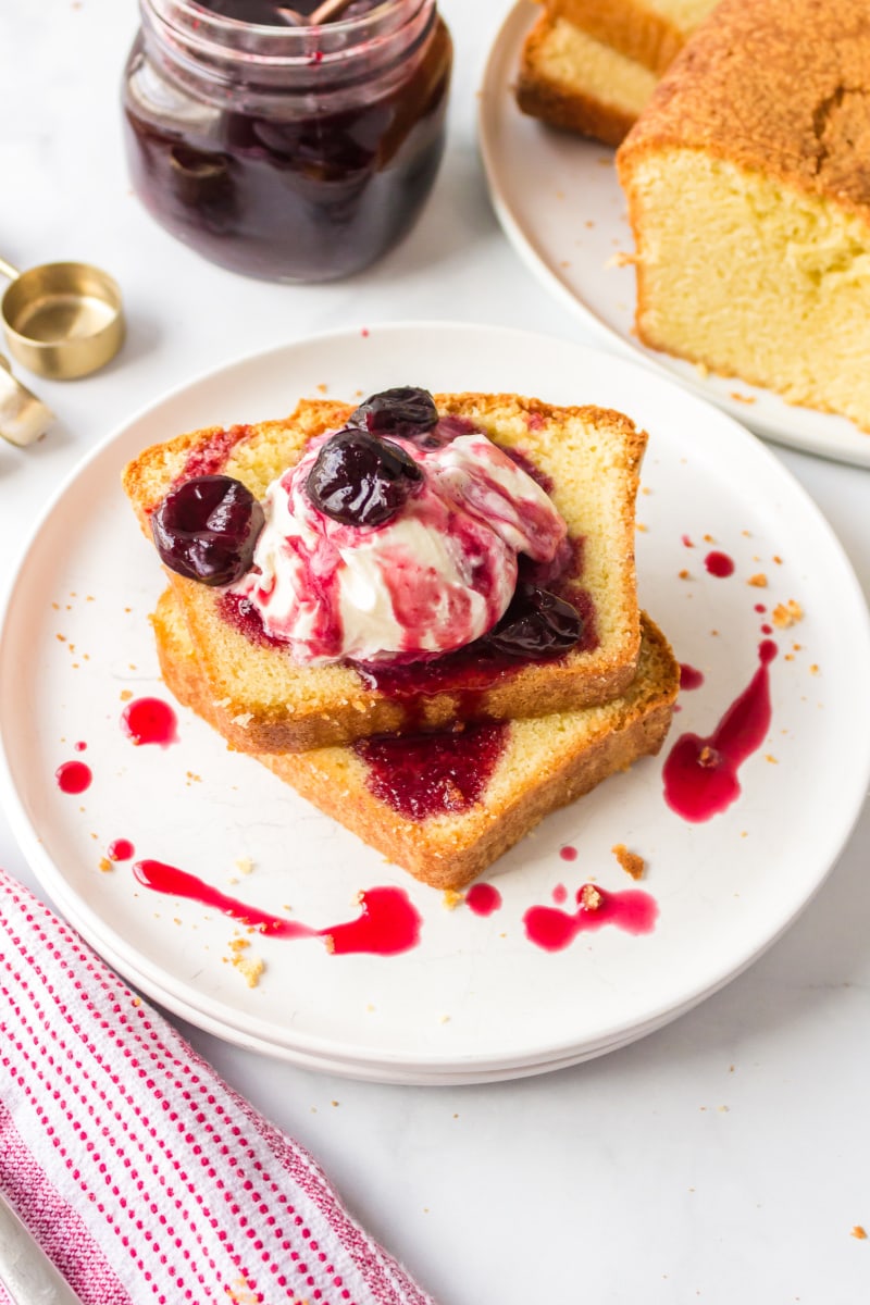 two slices classic pound cake on plate topped with ice cream and cherry sauce