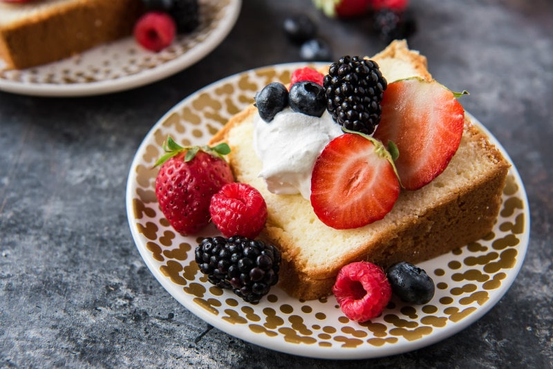 Slice of Cream Cheese Pound Cake with whipped cream and fresh berries