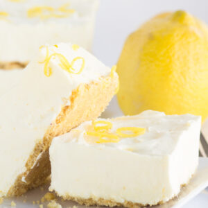 frozen lemon cheesecake squares displayed on white plate with a lemon