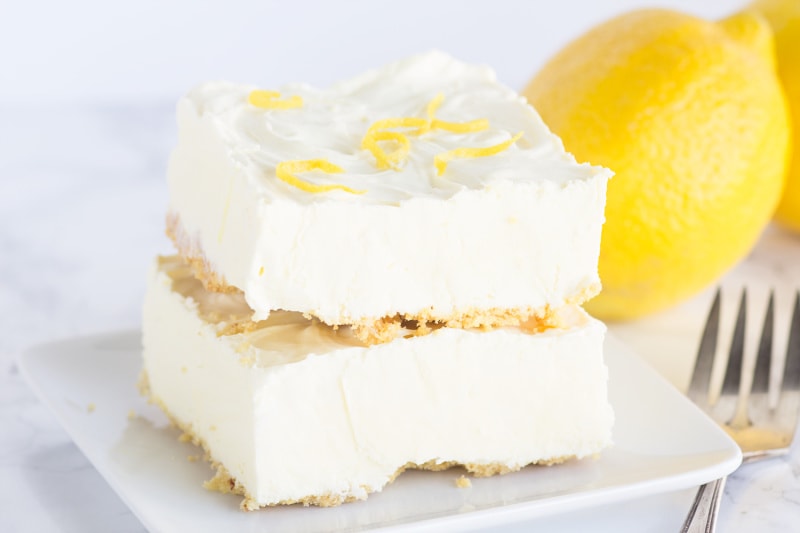 two frozen lemon cheesecake squares stacked on a white plate