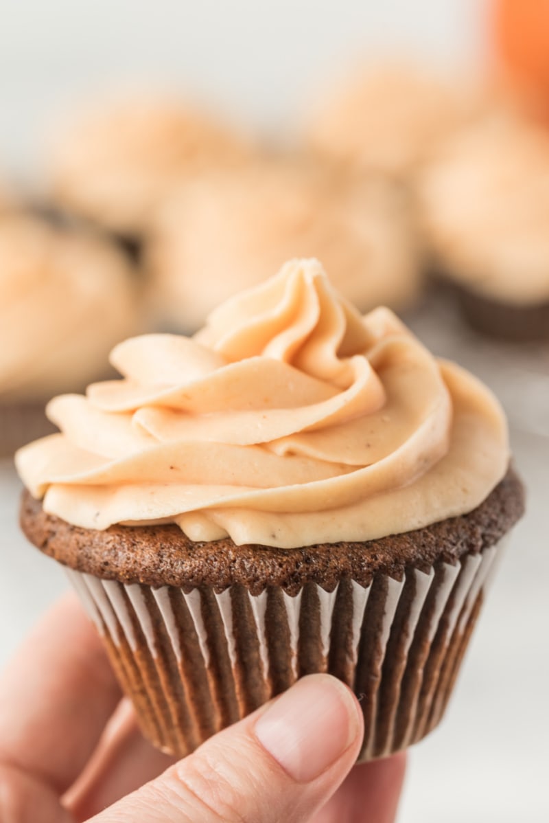hand holding cupcake with orange frosting