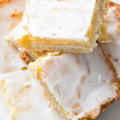 lemon bars stacked haphazardly on a white plate