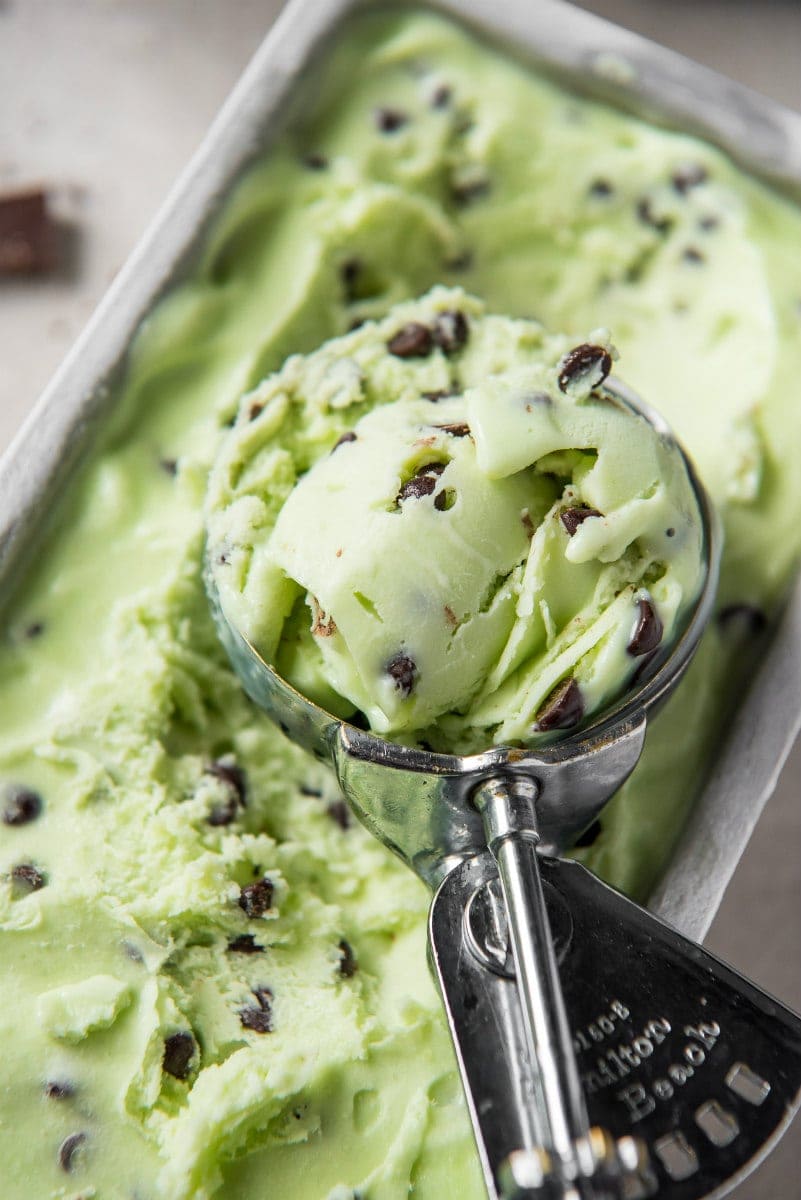 scooper with mint chocolate chip ice cream in it sitting on top of the ice cream container