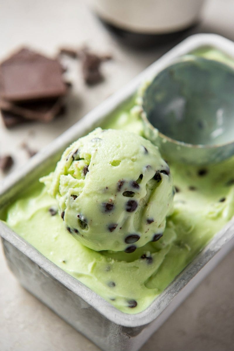 using a scooper to scoop mint chocolate chip ice cream out of the container