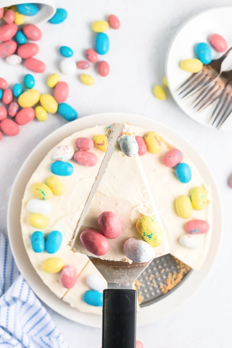 spatula taking out slice of malted mousse cake with colored eggs on top