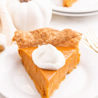 slice of pumpkin pie with whipped cream on plate