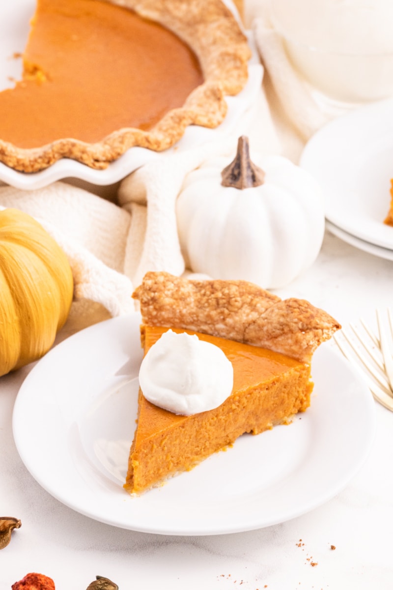 slice of pumpkin pie on plate with dollop of whipped cream