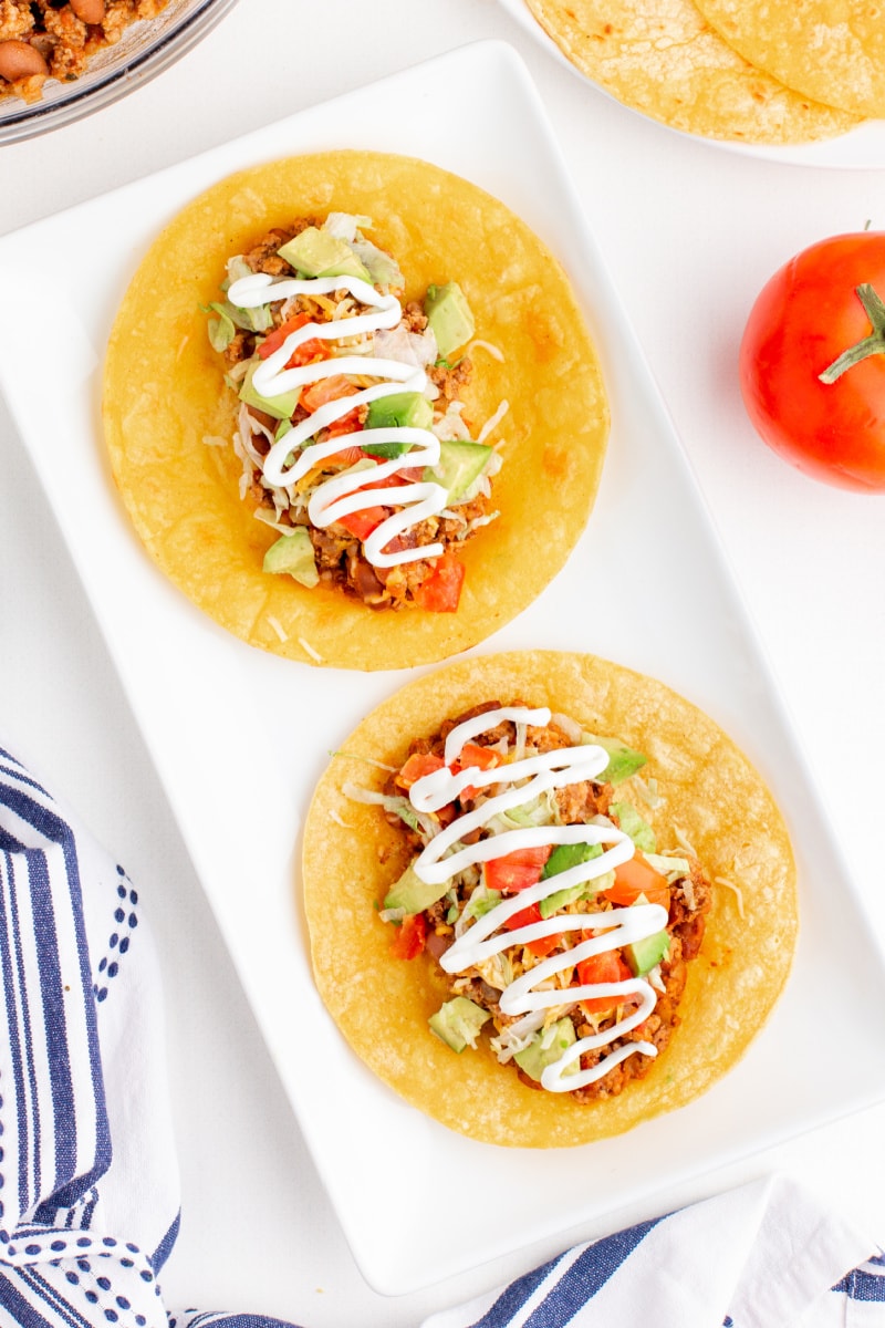 two tacos open faced on white plate