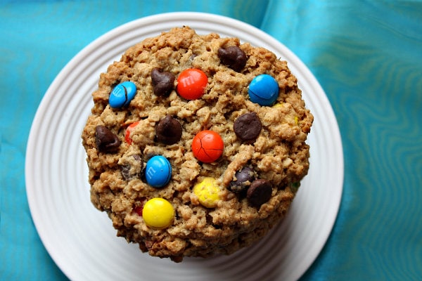 overhead shot of a stack of monster cookies on a white plate with a teal blue background