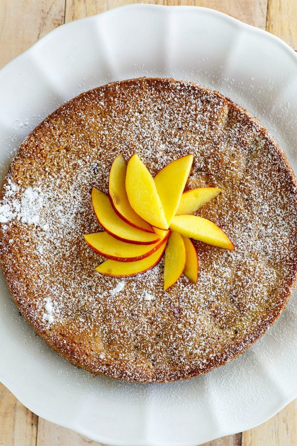 Overhead shot of nectarine coffee cake with fresh nectarines decoratively on top displayed on a white platter