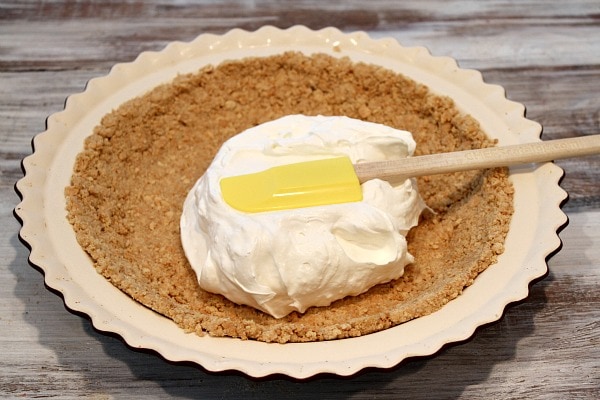 Graham Cracker Crust in pie plate with cream cheese layer spreading on top