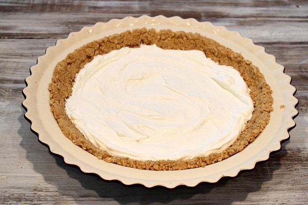 Graham cracker crust in pie plate with cream cheese layer on top