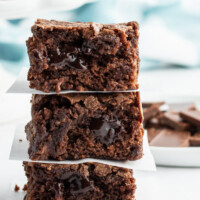 3 stacked brownies with chopped chocolate in the forefront