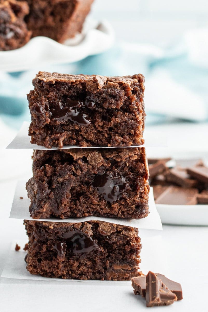 3 stacked brownies with chopped chocolate in the forefront