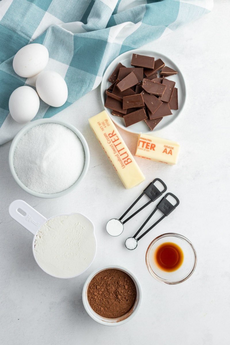 overhead shot of ingredients displayed for ooey gooey brownies- eggs, sugar, flour, cocoa, vanilla, butter, chocolate