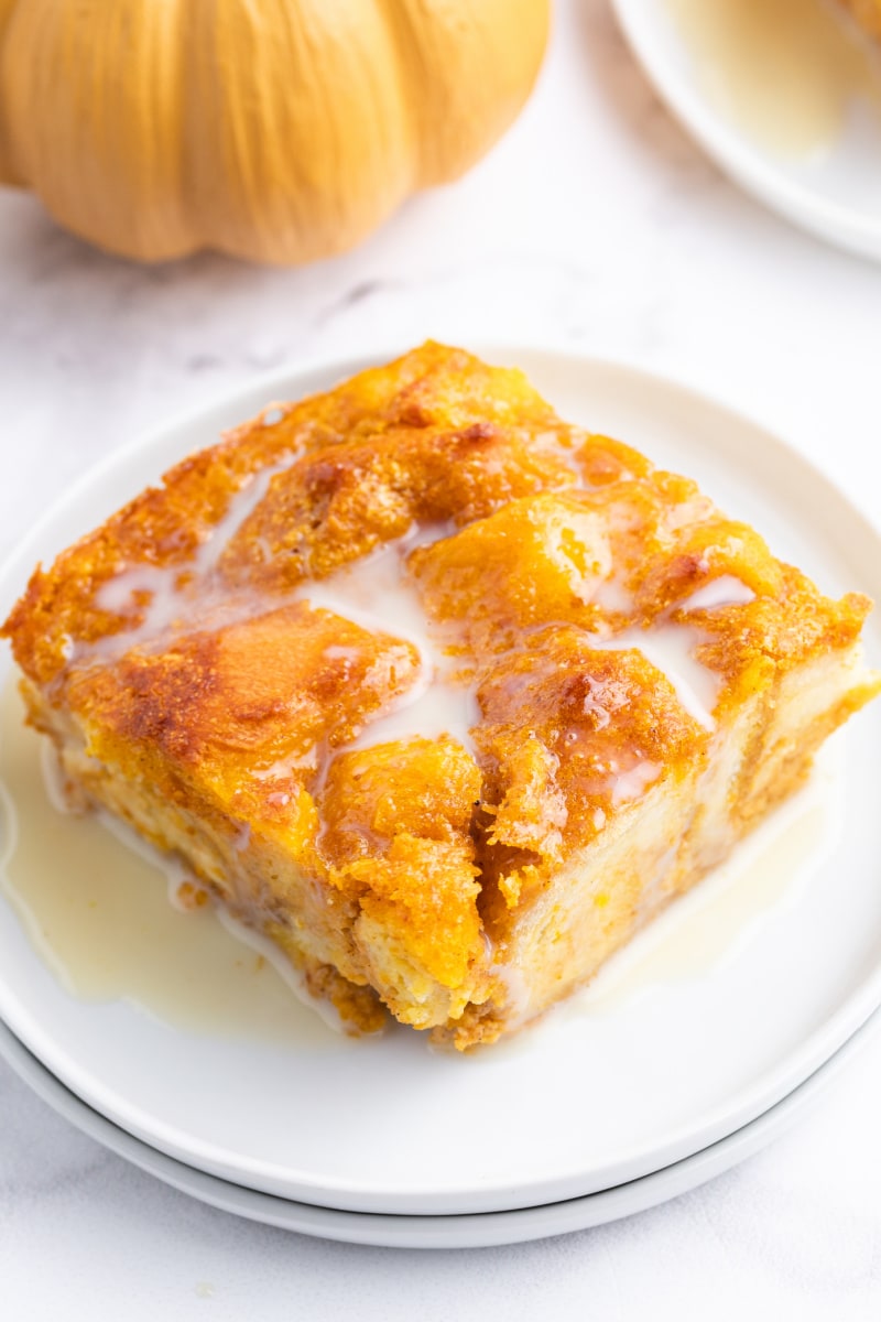 slice of pumpkin bread pudding with bourbon cream sauce on a white plate