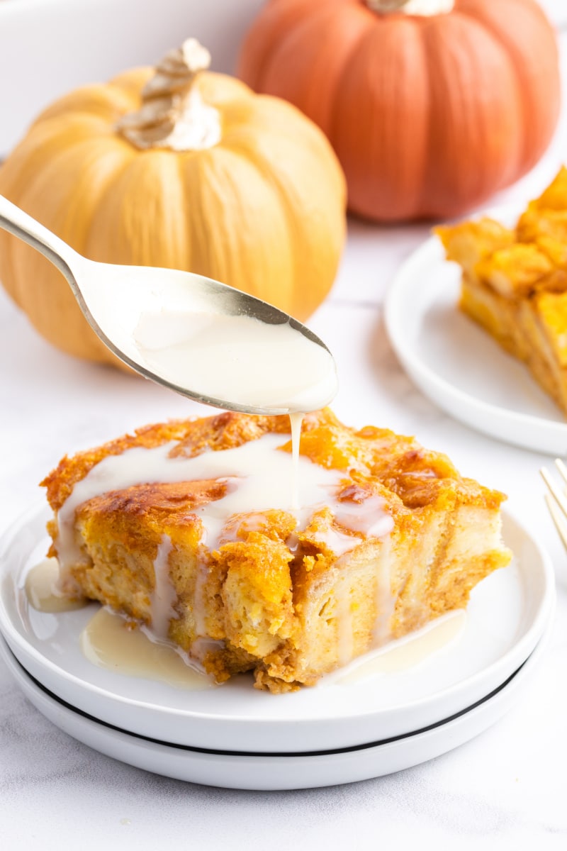 spooning bourbon cream sauce onto slice of pumpkin bread pudding