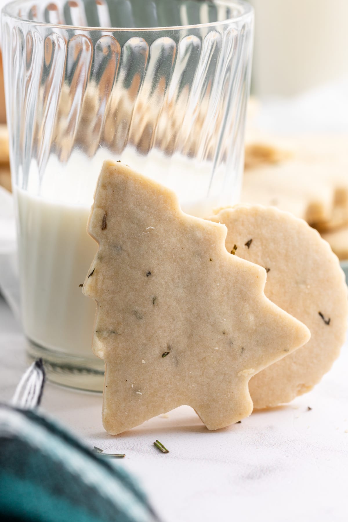 christmas tree cookie leaning against glass of milk