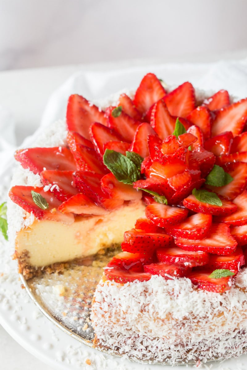 strawberry coconut cheesecake on platter with a slice removed