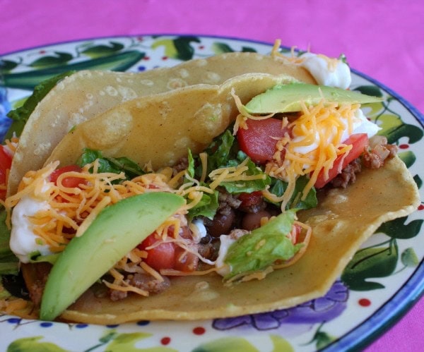 Taco on colorful plate with fixings added to it