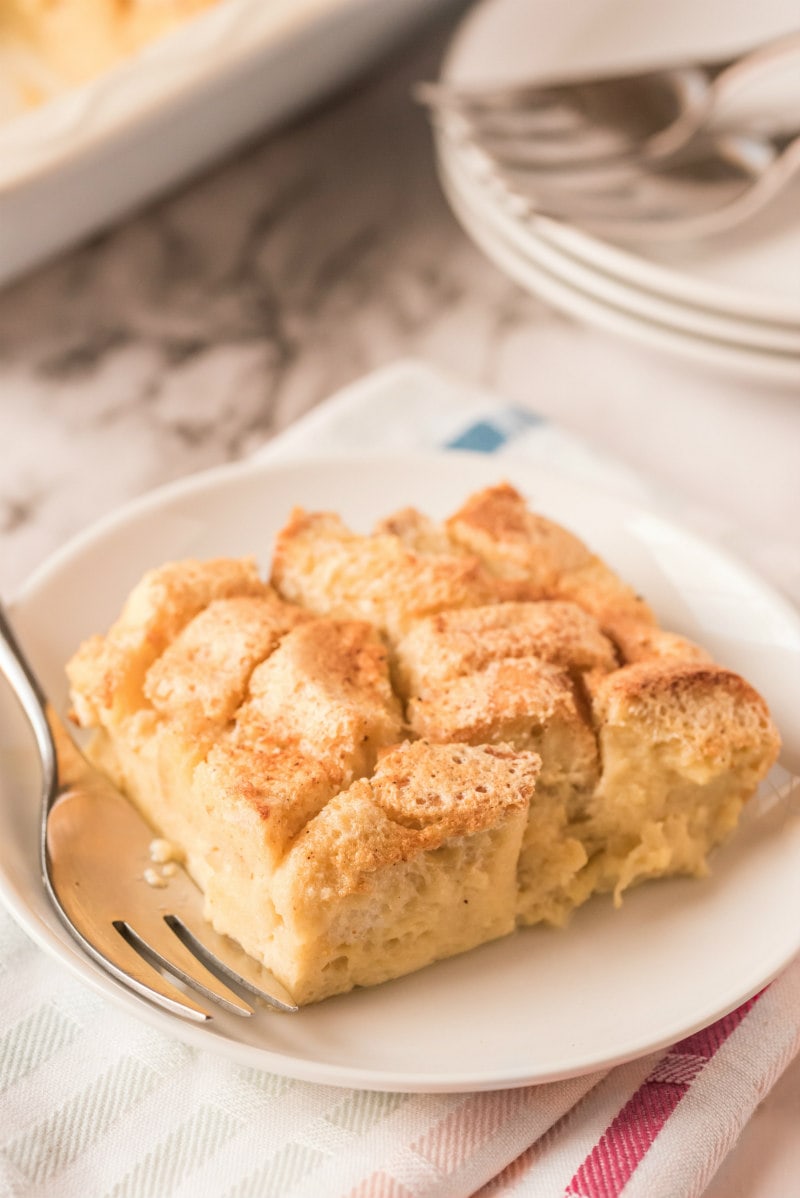 slice of bread pudding on white plate with fork