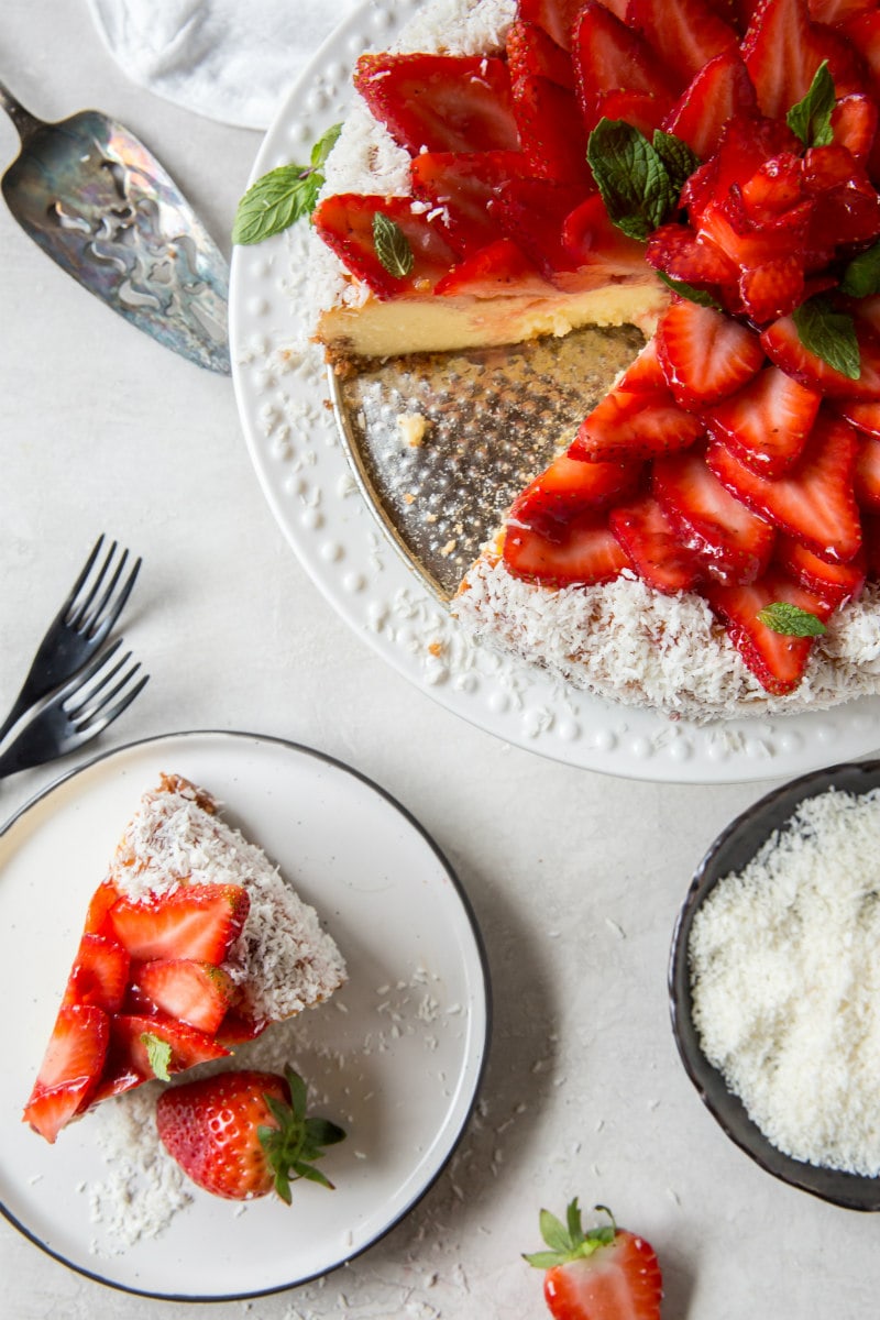 overhead shot of strawberry coconut cheesecake slice removed and slice of the cheesecake on a white plate