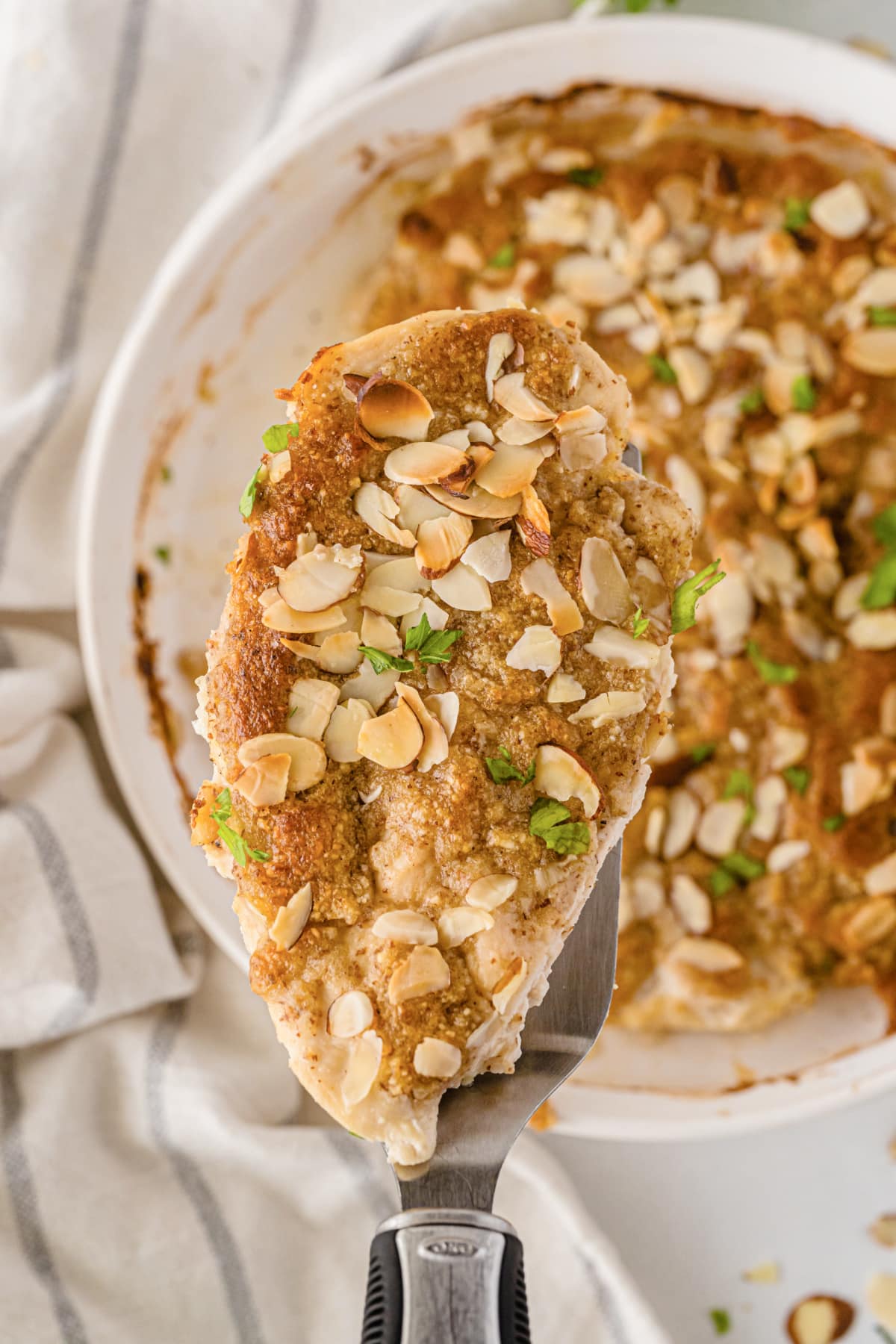 Spatula taking almond butter chicken out of dish