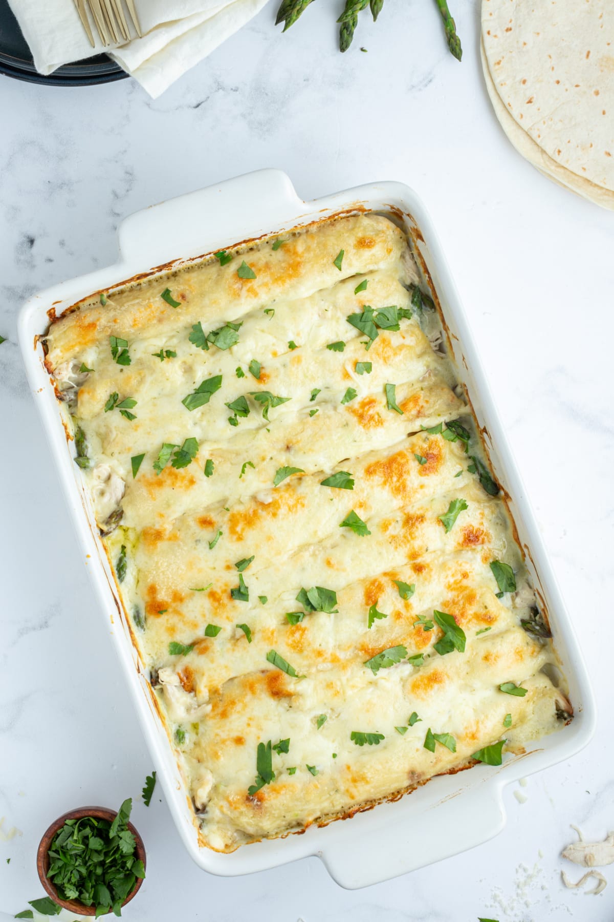 asparagus and chicken enchiladas in a baking pan