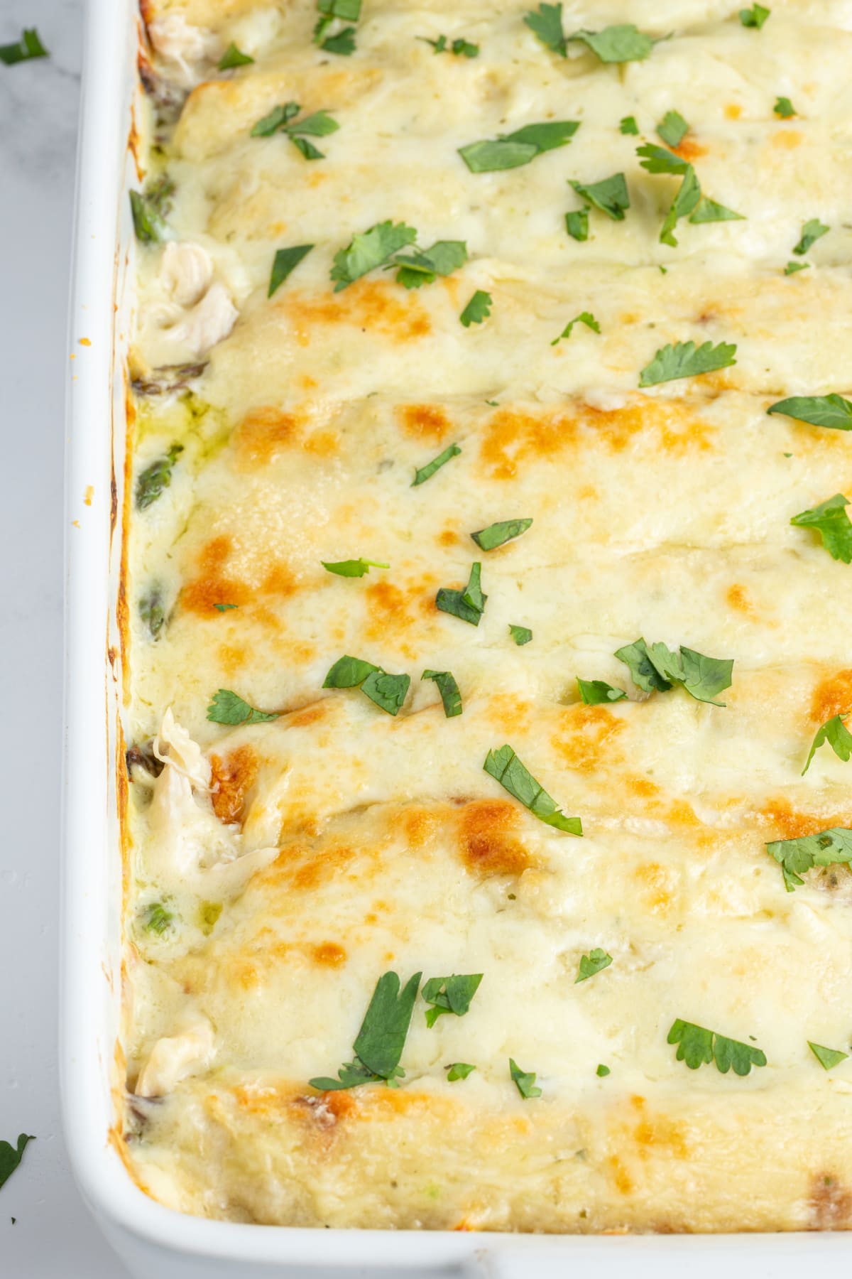 asparagus and chicken enchiladas in a baking pan