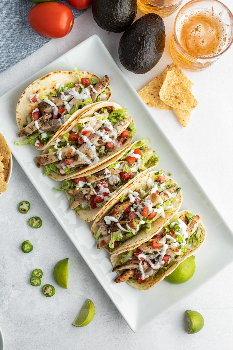 overhead shot of a bunch of tacos on a white platter