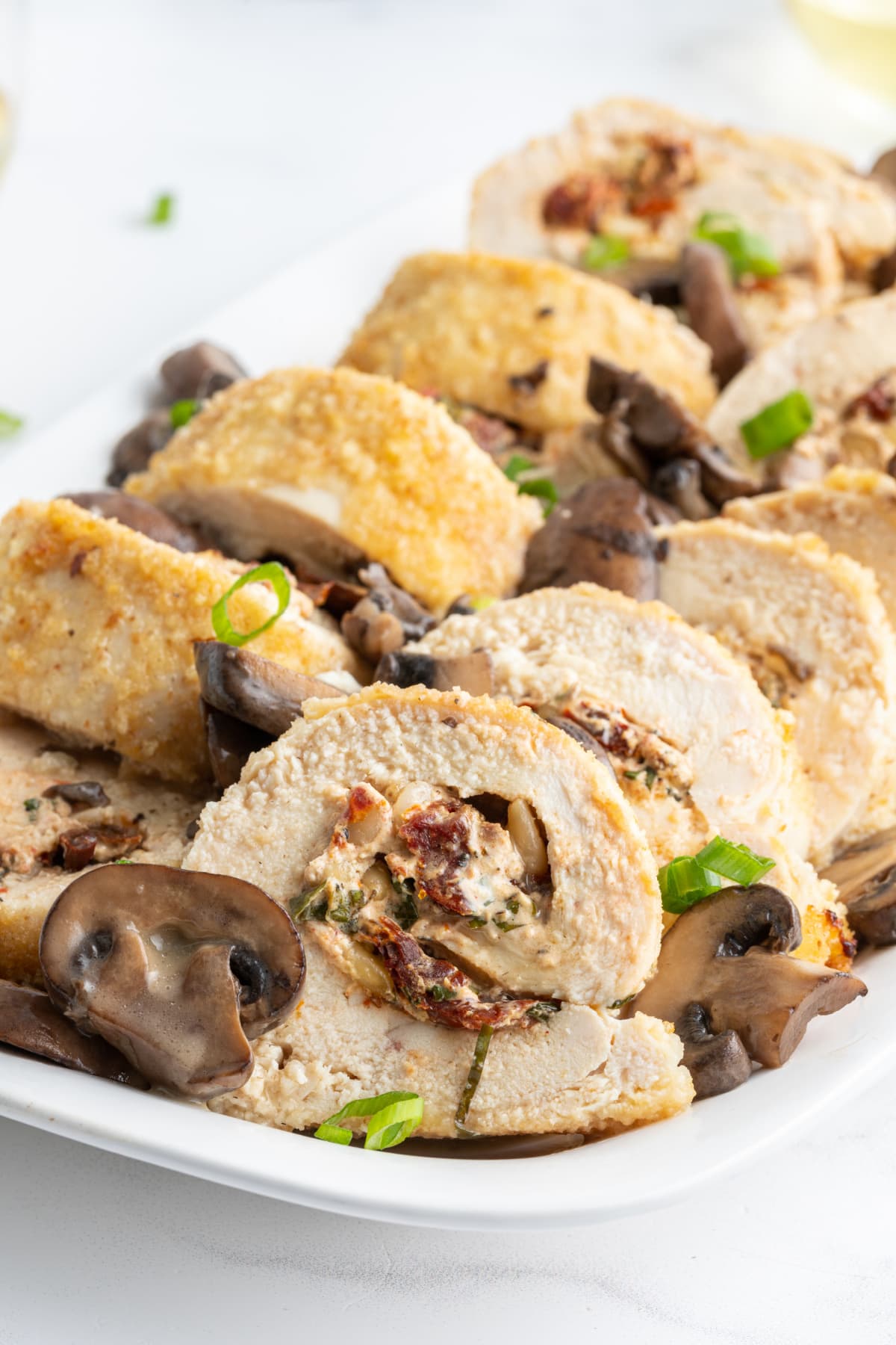 chicken breasts stuffed with goat cheese and sun-dried tomatoes sliced on platter