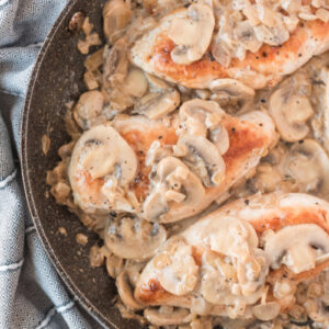 chicken breasts in a skillet with madeira mushroom sauce