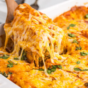 spatula scooping up chicken and spinach enchiladas