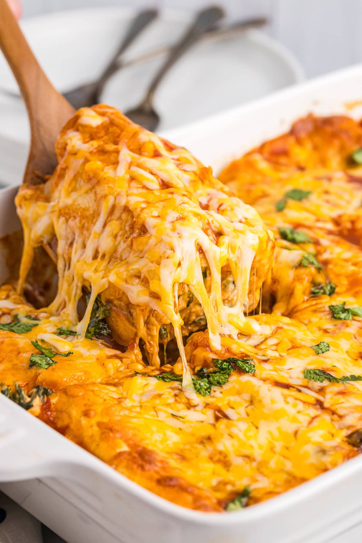 spatula scooping up chicken and spinach enchiladas