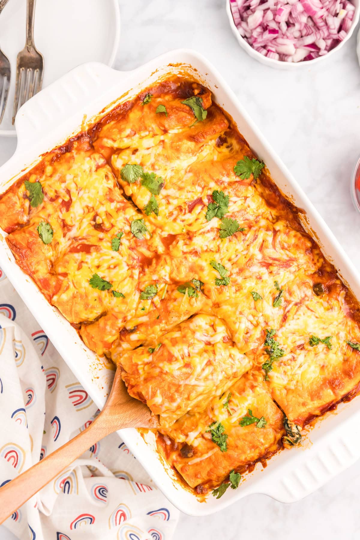 overhead shot of pan of chicken and spinach enchiladas cut into slices