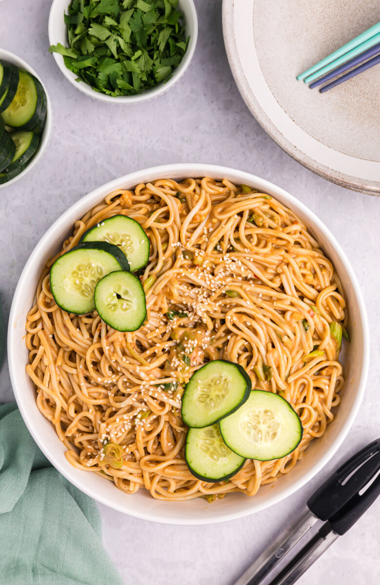cold sesame noodles in a bowl with cucumber slices