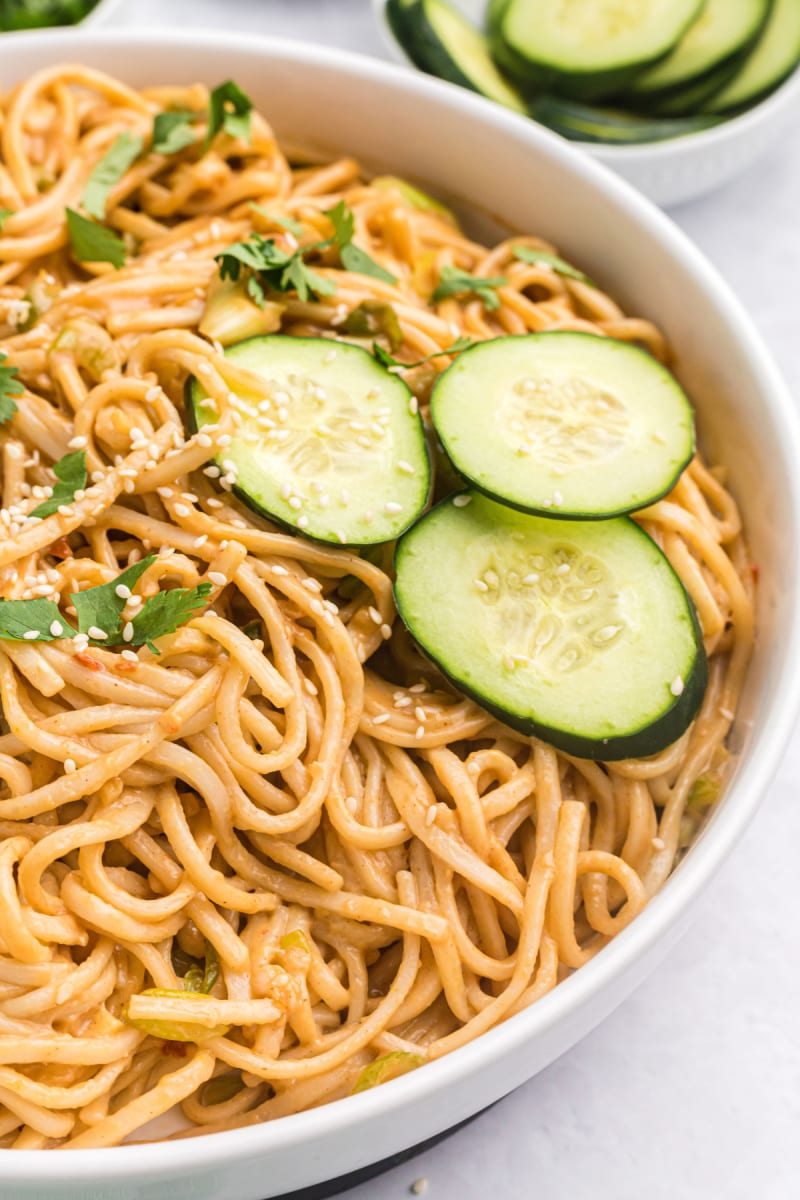 cold sesame noodles in a bowl with cucumber slices