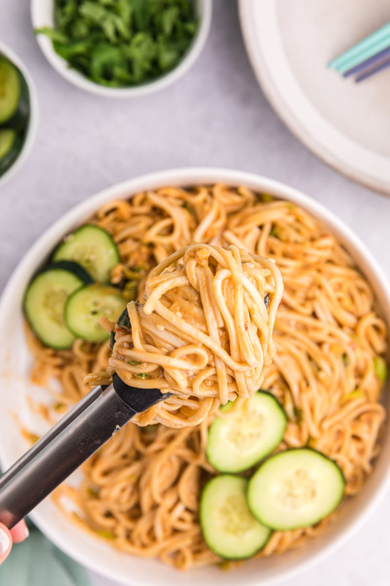 cold sesame noodles in bowl with tongs
