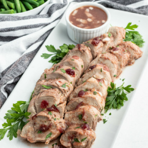 sliced cranberry pork tenderloin on a white platter