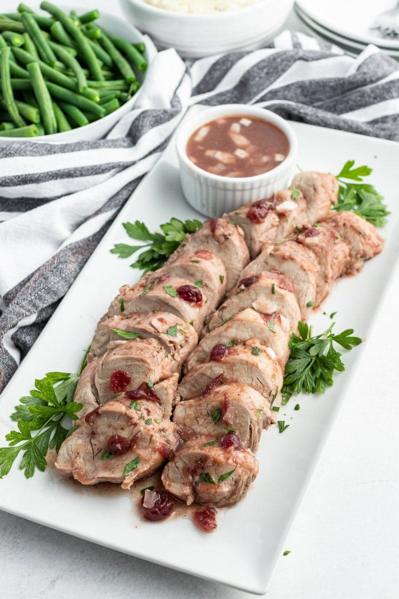 sliced cranberry pork tenderloin on a white platter