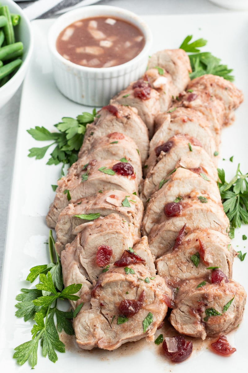 sliced cranberry pork tenderloin on white platter