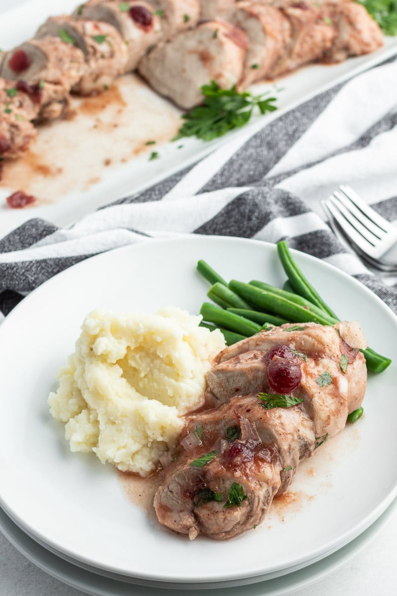 serving of cranberry pork tenderloin and potato on white plate