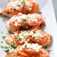 feta topped broiled chicken on a white plate