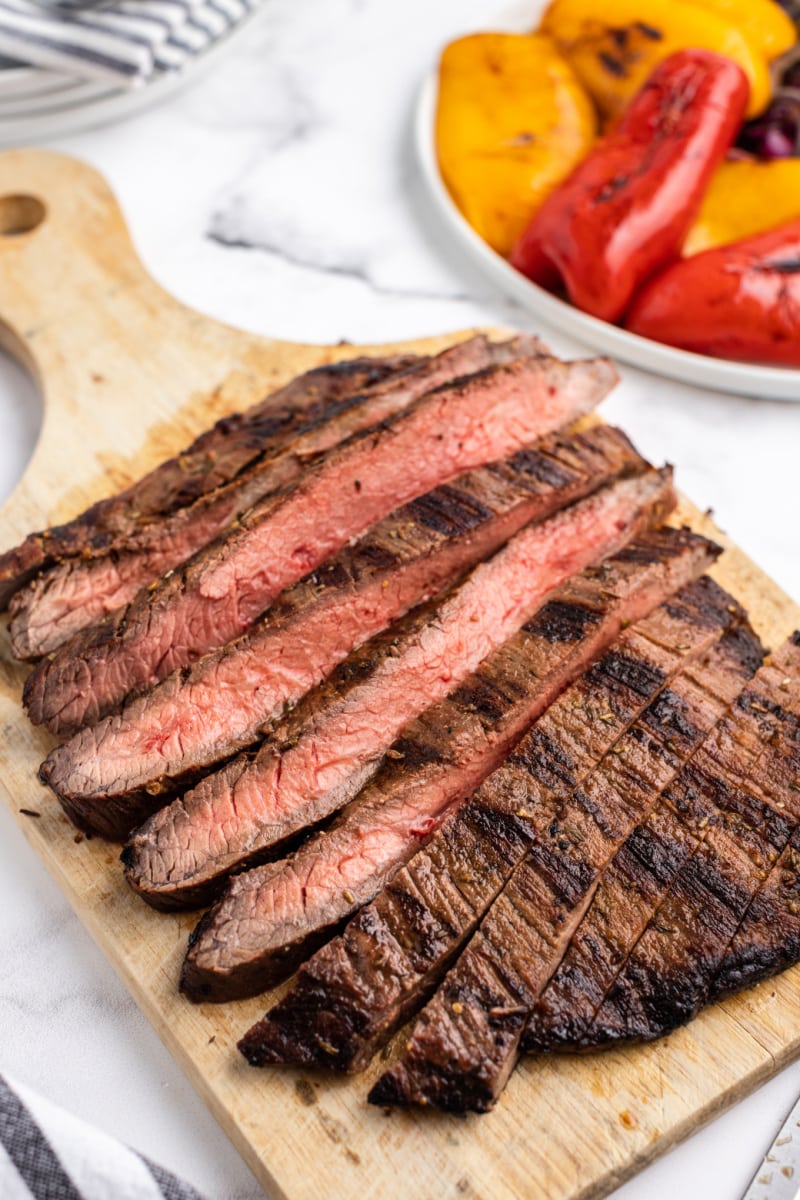 grilled flank steak cut into slices on cutting board