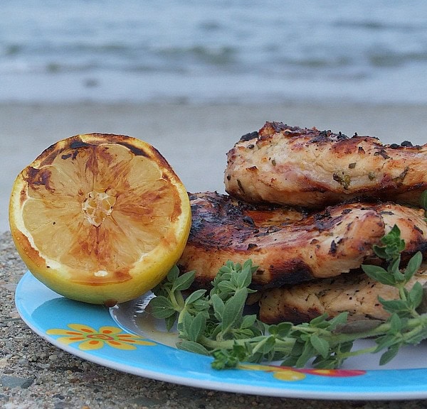 Grilled Chicken with Lemon and Oregano on a blue plate with grilled lemon and fresh oregano