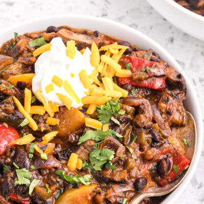 grilled vegetable chili in a bowl garnished with sour cream and cheese