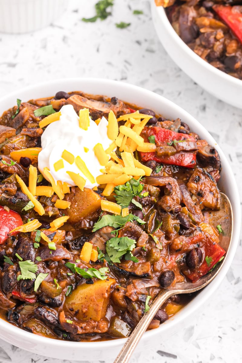 grilled vegetable chili in a bowl garnished with sour cream and cheese