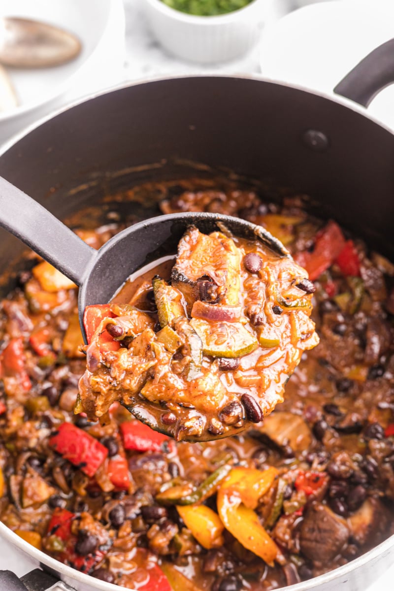 ladle full of grilled vegetable chili coming out of pot of chili