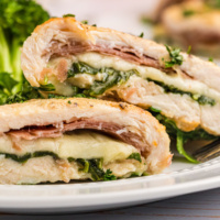 gruyere arugula and prosciutto stuffed chicken breasts cut open on a plate